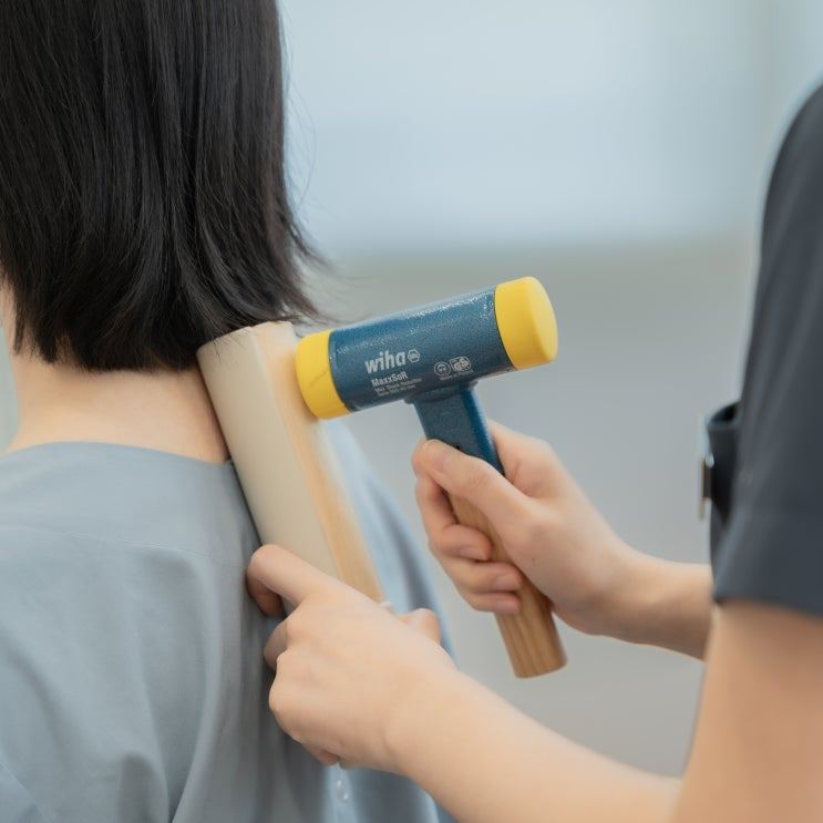 목 뒤에 충격파 기기를 대는 치료 모습