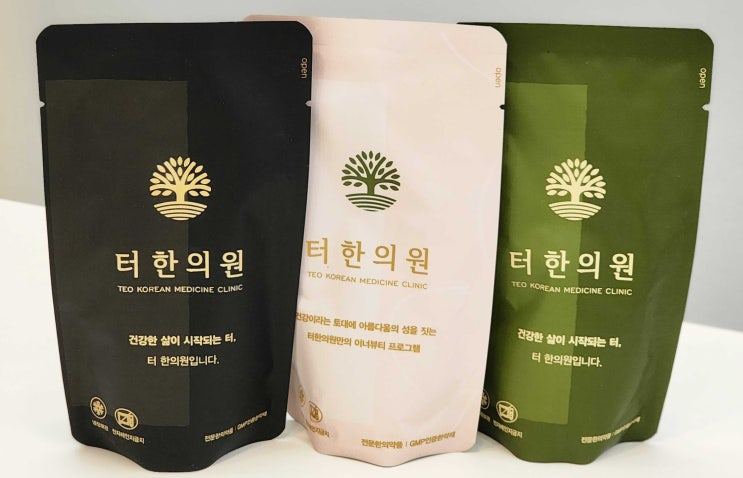 터한의원 로고가 인쇄된 검정색, 연분홍색, 녹색 한약 파우치 세 개